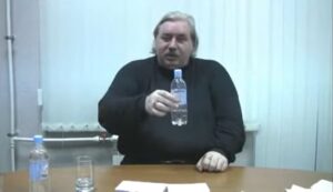 Николай Левашов показывает пластиковую бутылочку с водой объёмом 0,5 л
